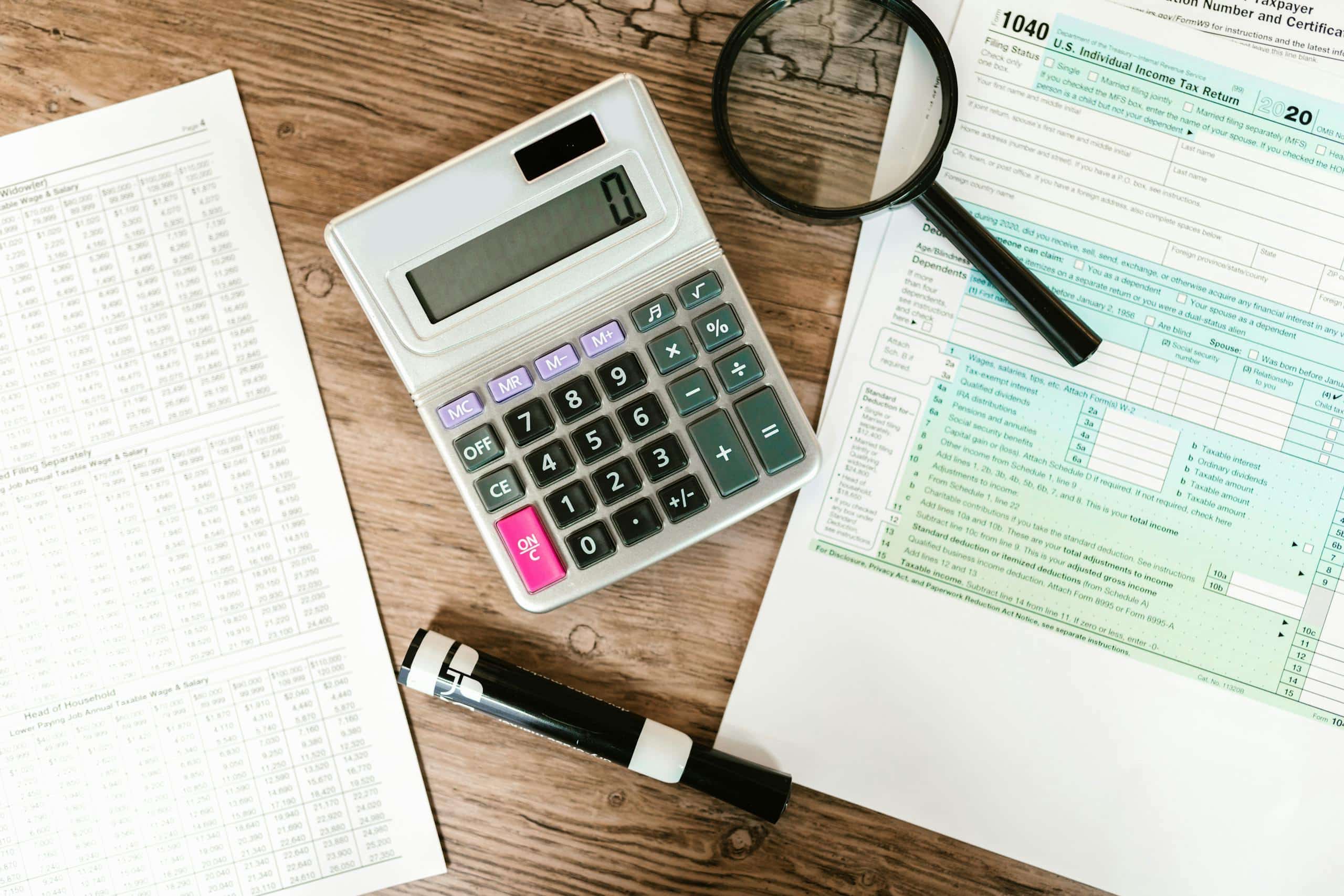 gray-calculator-and-black-magnifying-glass-on-brown-wooden-surface-7821685-scaled.jpg